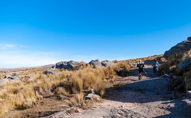 Mountain landscape with blue sky and woman and man walking in the middle of the mountain
