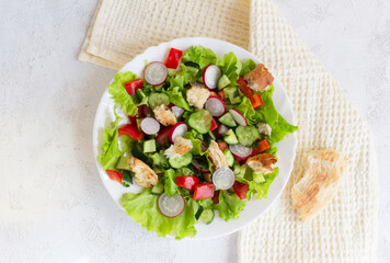 Flat lay. Fattoush salad with tomato, cucumber, radish and toasted pita bread, oil spilled in a white plate on a napkin