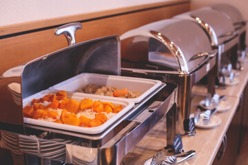 Decorated breakfast catering setting at the hotel, with variety of dishes: cereal, corn flakes, vegetables, toast, pancakes, pastry, cupcakes and other food