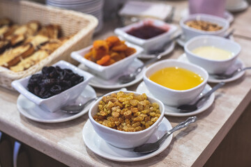 Decorated breakfast catering setting at the hotel, with variety of dishes: cereal, corn flakes, vegetables, toast, pancakes, pastry, cupcakes and other food