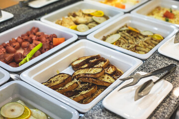 Decorated breakfast catering setting at the hotel, with variety of dishes: cereal, corn flakes, vegetables, toast, pancakes, pastry, cupcakes and other food