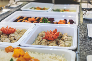 Decorated breakfast catering setting at the hotel, with variety of dishes: cereal, corn flakes, vegetables, toast, pancakes, pastry, cupcakes and other food