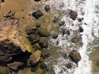 Beach, water with sand and stones, top view. Ocean or sea, rocky beach.