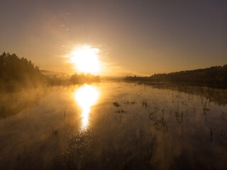 Sunset or dawn on a morning lake or swamp, steam and haze