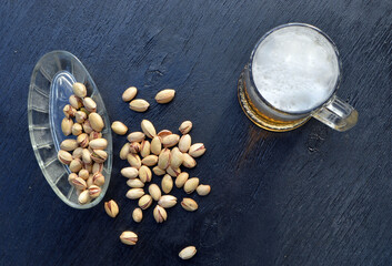 
a mug of fresh beer and delicious pistachios stands on the table