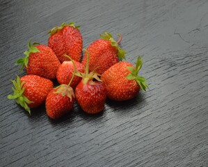 
tasty and healthy strawberry lies on a black wooden background