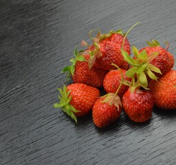 
fresh strawberries lie on a black wooden table