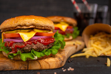Hamburger on a black wooden background with french fries and soda closeup, fast food