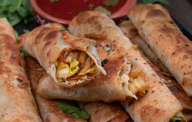 Vegan cabbage and carrot flautas served with salsa and guacamole on wooden table, close up