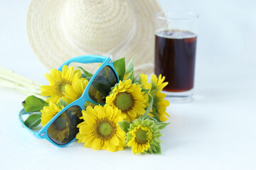 麦わら帽子とレモンイエローのヒマワリの花束とサングラスとコーヒー