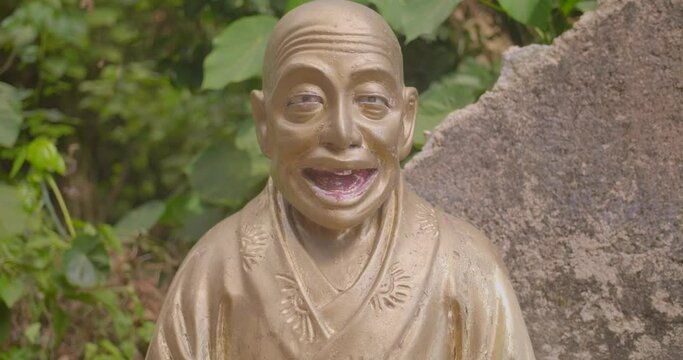 Beautiful old golden buddha statue looking at the camera It has its mouth open. Handheld professional 4k shot. High dynamic range footage.