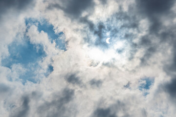 Solar Eclipse in blue sky among the clouds