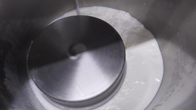 Inside steel vat, filling factory cauldron with milk for pasteurization process