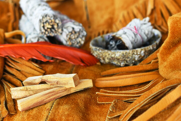 Fototapeta na wymiar An image of three palo santo smudge sticks and white sage on an old vintage leather coat. 
