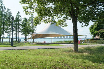 A sailboat tent by the lake, public park scenery.