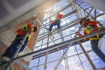 Construction workers in safety uniform install reinforced steel scaffolding at outdoor construction...