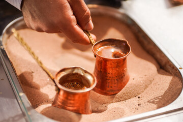 male hand preparing Turkish coffee in burning sand at Souq Waqif