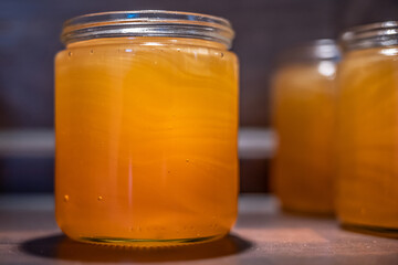 Golden yellow honey in glass jar on wooden board Closeup Copy space comp frame empty textspace