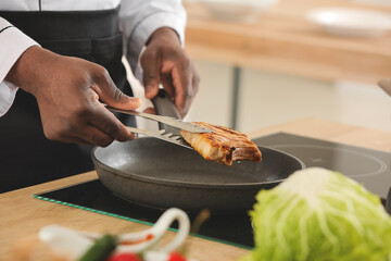 Male African-American chef cooking in kitchen, closeup