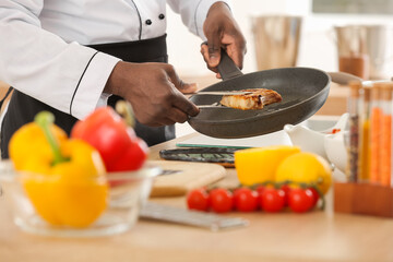 Male African-American chef cooking in kitchen, closeup