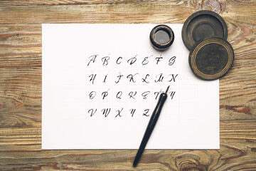 Nib pen with alphabet and ink on table