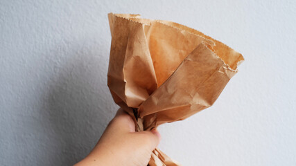 Close-up female holds in hand brown clear empty blank craft paper bag.