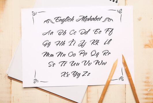 Notebook and paper sheet with alphabet on table