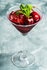 Cherry cocktail in martini glass with berries and mint leaves. Selective focus. Shallow depth of field.