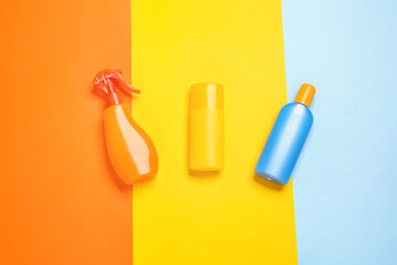 Bottles of sunscreen on color background