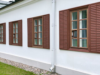 row of classical wooden windows with shutters on white building facade wall