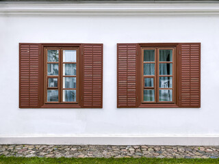 two traditional windows with open wooden shutters on the old building's stucco wall 