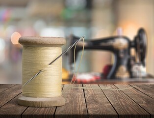 Needle and a spool of thread on the wooden desk