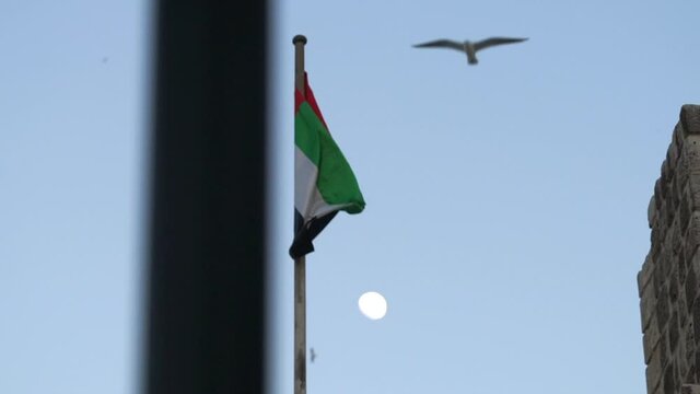 Scenic View Of UAE Flag And Moon In The Sky In Deira, Dubai On A Sunset - medium shot