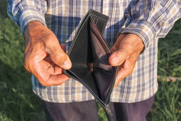 Elderly hands is opening and showing an empty wallet from poverty close-up.