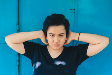 Asian beautiful short hair girl on blue background with sharp looking and serious face expression...