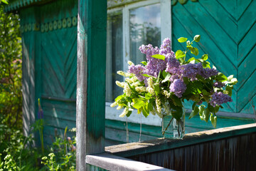 Fototapeta na wymiar bouquet of spring lilac flowers in a vase on the porch of the house