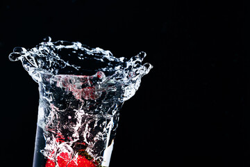 Strawberries fall into a glass of water.