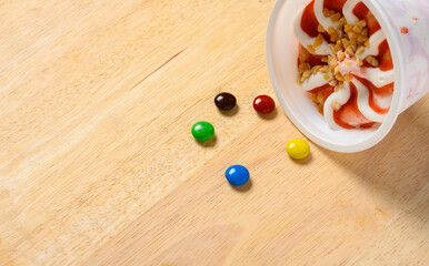 cup of fresh strawberry and vanilla flavor ice cream sundae with chocolate buttons next to it