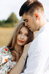 Fototapeta premium Loving couple in a wheat field. Beautiful blonde with her boyfrinds.