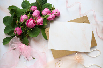 mock wedding card. a bouquet of pink roses, a wedding ring and an envelope with place for text. congratulation. invitation
