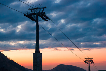 Mountain ski lift on sunset background.