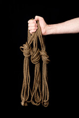 A man holds three knotted ropes in his hand. Isolated on a black background.
