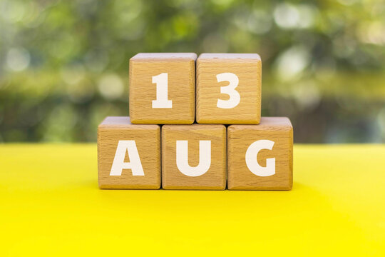 Wood cubes with text 13 AUG. 13th of August -International Lefthanders Day. Blurred natural green background. Summer time.