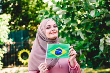 Muslim woman in hijab holds flag of Brazil