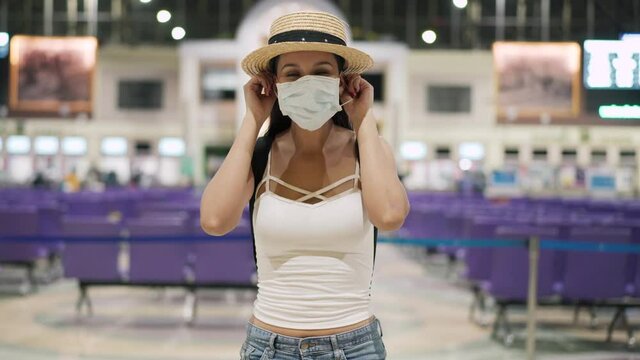 Young brunette woman traveling in Thailand in train station during pandemic Coronavirus. 20s Hispanic in a protective mask wear summer sleeveless clothes and backpack in Asia