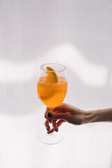 Woman holding glass of summer aperol spritz cocktail.