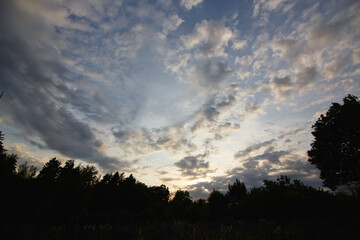 Natural sunset, sunrise over the forest. Bright dramatic sky and dark earth. Rural landscape under a picturesque summer dramatic sky At sunset sunrise. Horizon.