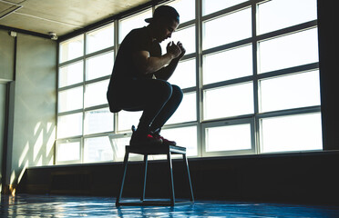 Young guy athlete is engaged in exercise and jumping in the gym. Silhouette photography