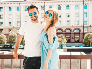 Portrait of smiling beautiful girl and her handsome boyfriend.Woman in casual summer jeans dress.Happy cheerful family.Female having fun.Couple posing on the street background in sunglasses