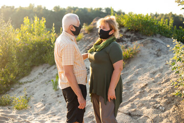 Senior couple wearing medical masks to protect from coronavirus in summer day, coronavirus quarantine